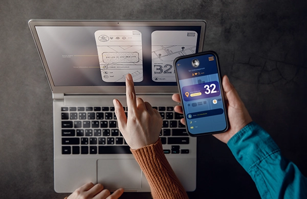 ノートPCとスマートフォンの画面を指差して操作を確認する様子